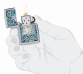 Srebrna Zippo z minimalistycznym wzorem liścia lotosu wykonanym w stylu kamienia.
